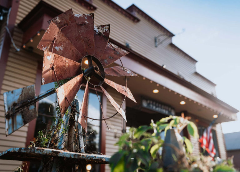 Rustic windmill sculpture with weathered blades and metal pole, surrounded by greenery in Williamson County, Tennessee.