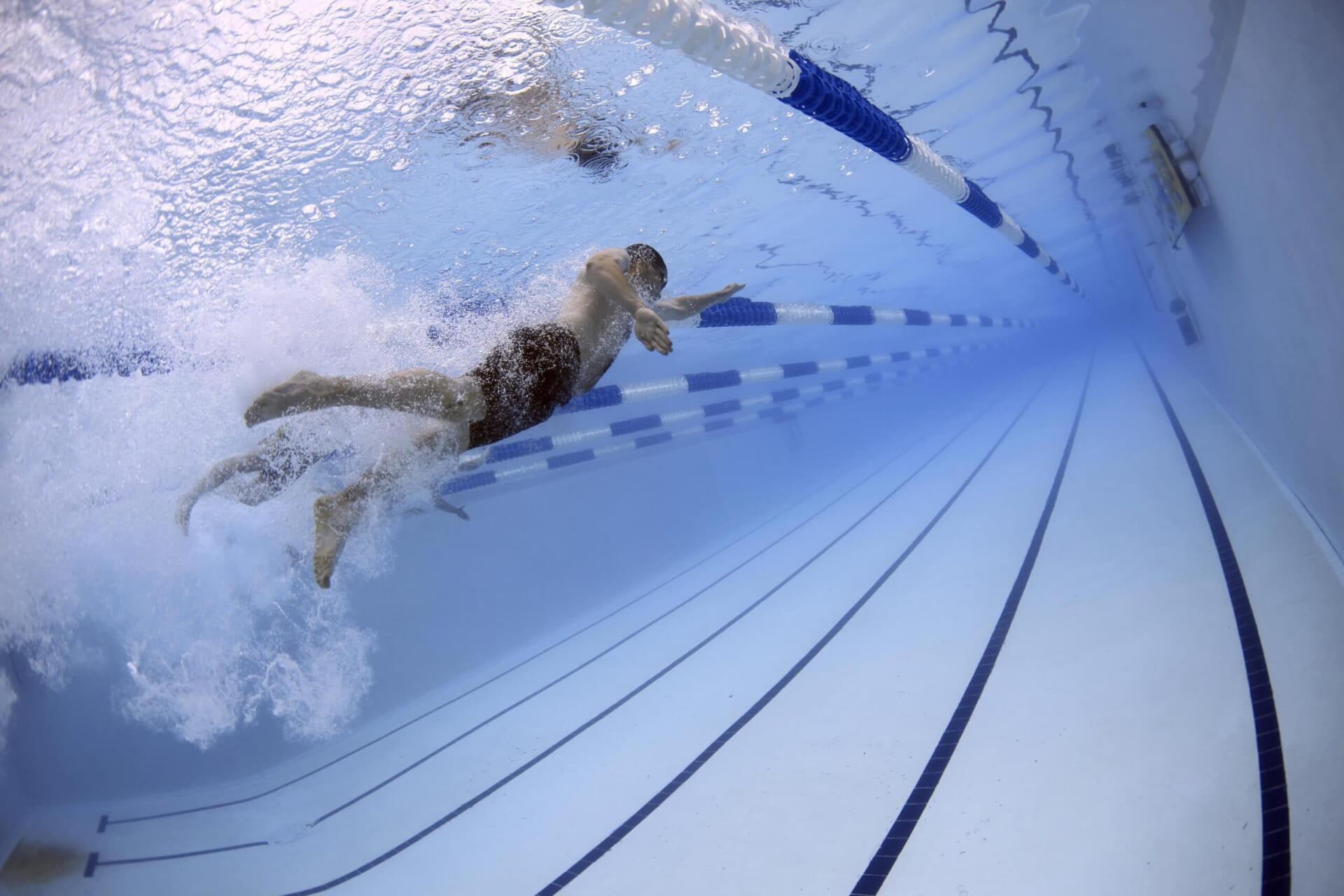 A swimmer races underwater in a long, blue pool with lane dividers in Williamson County, Tennessee.