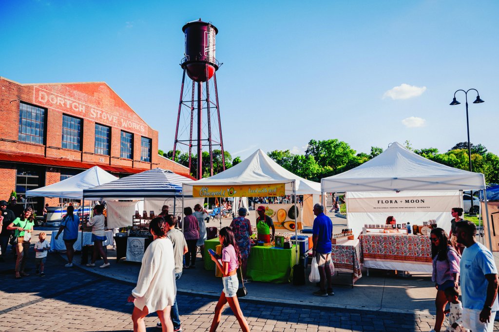 A bustling outdoor market with colorful tents, a historic water tower, and a lively crowd shopping and socializing in Williamson County, Tennessee.
