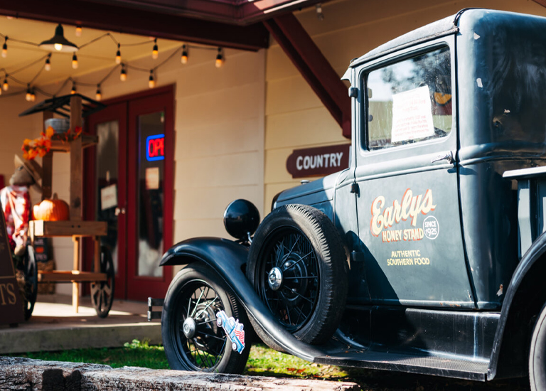 Vintage truck with 'Earl's Honey Stand' sign parked outside a country store with pumpkins in Williamson County, Tennessee.