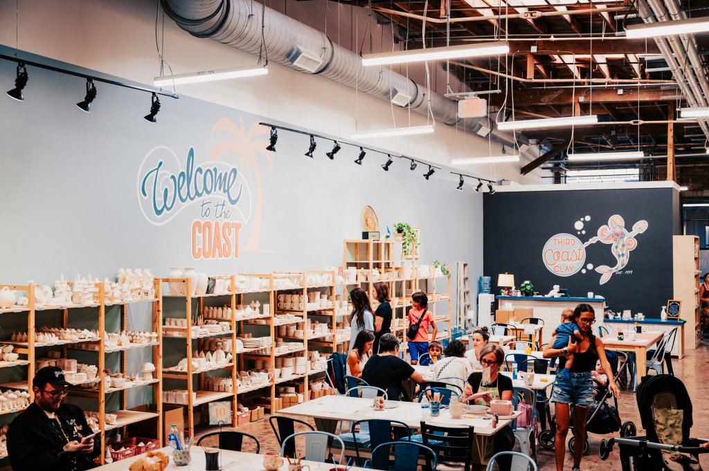 A bustling ceramic studio with people painting pottery and enjoying refreshments at tables in Williamson County, Tennessee.