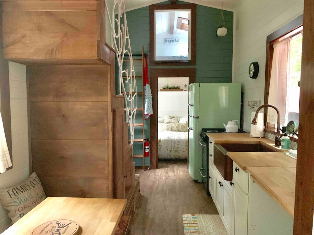 A cozy, compact kitchen with a green fridge, wooden cabinets, and a rustic dining table in Williamson County, Tennessee.