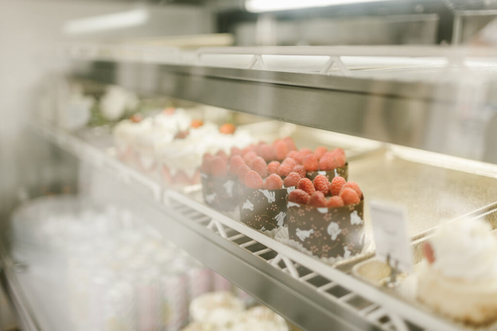 A bakery display case filled with various desserts, including raspberry-topped cakes and cheesecakes in Williamson County, Tennessee.