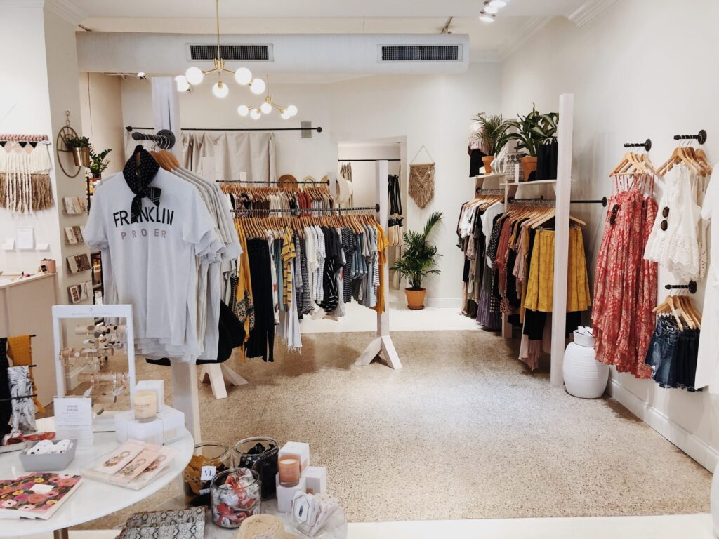 A brightly lit boutique with clothing racks, a white table, and hanging plants in Williamson County, Tennessee.