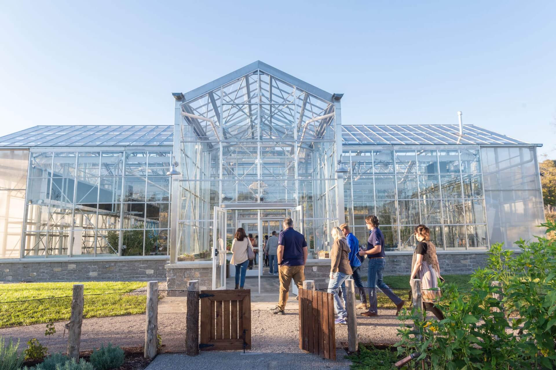A group of people enters a large, modern greenhouse with a glass roof and walls in Williamson County, Tennessee.