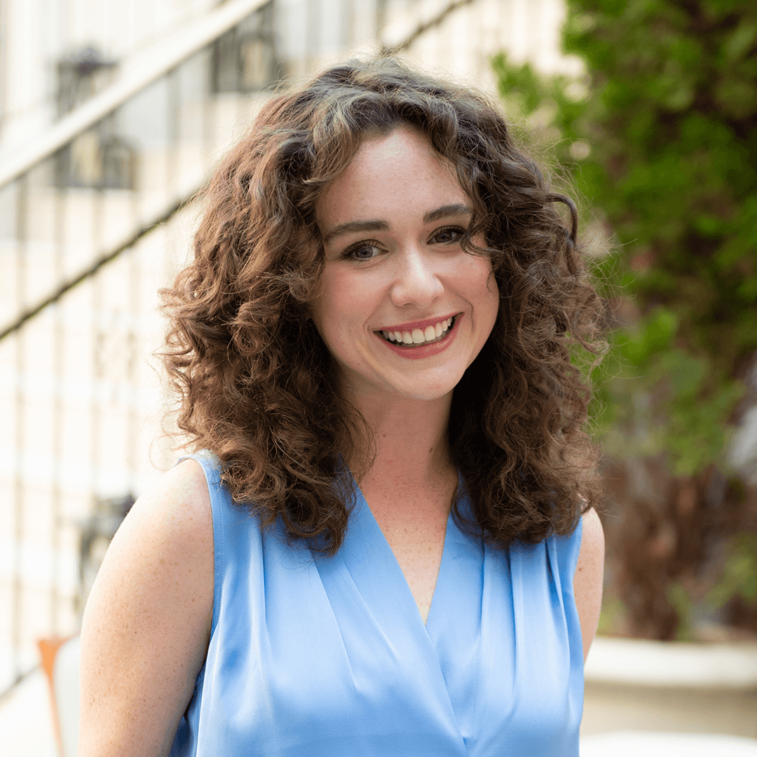 A woman with curly hair is smiling brightly, wearing a blue sleeveless top in Williamson County, Tennessee.
